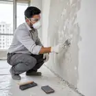 Worker cleaning dust, grease and loose particles from a wall before applying Acrylic Wall Putty.