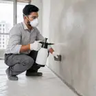 Worker lightly moistening a clean wall surface before applying Acrylic Wall Putty.
