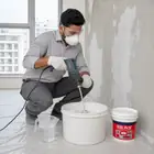 Worker mixing Acrylic Wall Putty with clean water to form a smooth paste.