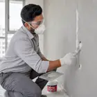 Worker filling cracks, holes and uneven areas uniformly with Acrylic Wall Putty.