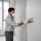 Worker applying Acrylic Wall Putty in a thin layer for an even finish.
