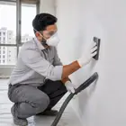Worker sanding the dried Acrylic Wall Putty surface with fine emery paper.