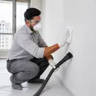 Worker wiping sanding dust from the wall before applying primer or paint.